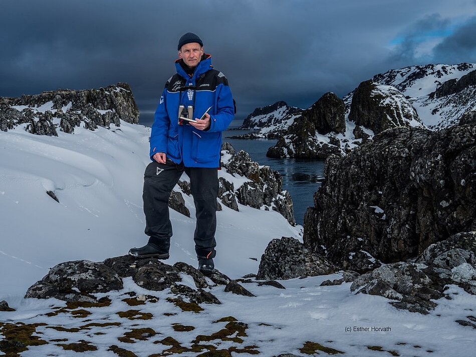Der Ökologe Fritz Hertel steht in dicker Winterbegleitung auf einem kleinen Felsen in der Antarktis