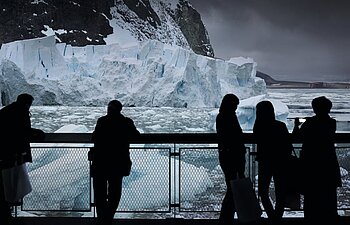 Mehrere Besucher betrachten Eisberge im 360°-Panorama ANTARKTIS.